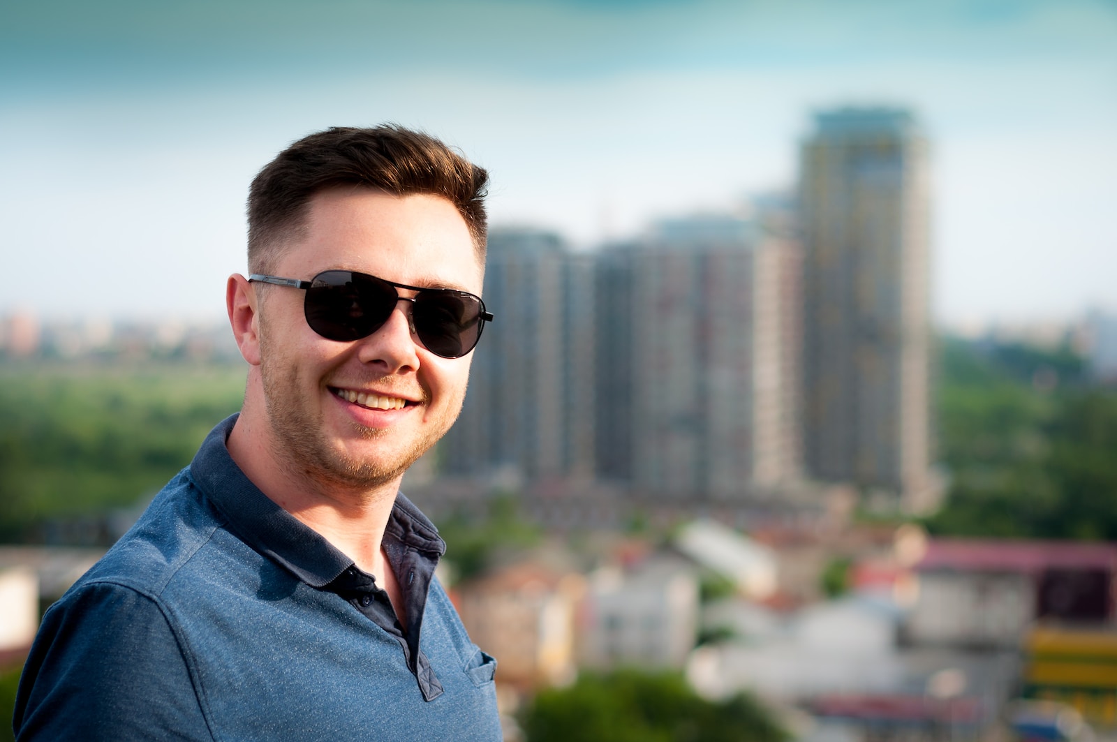 man wearing blue polo shirt with building background