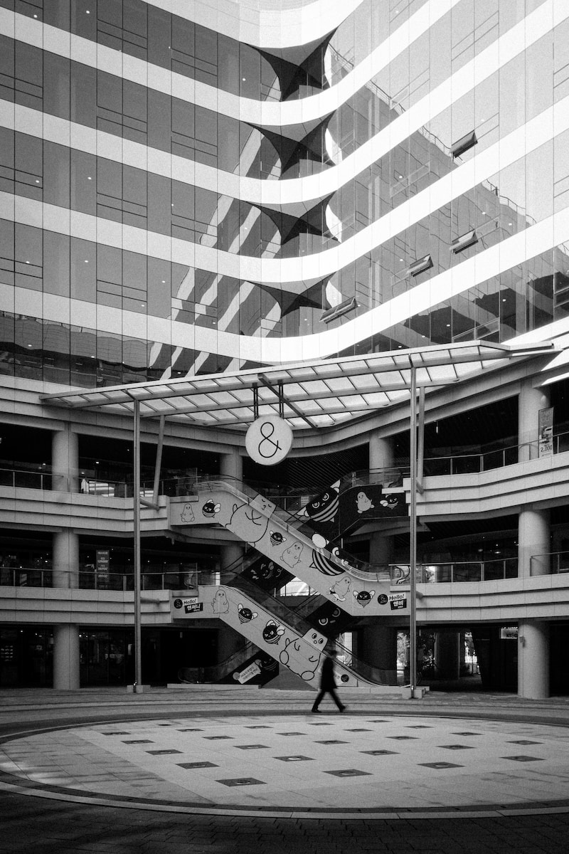 a black and white photo of a person walking past a building